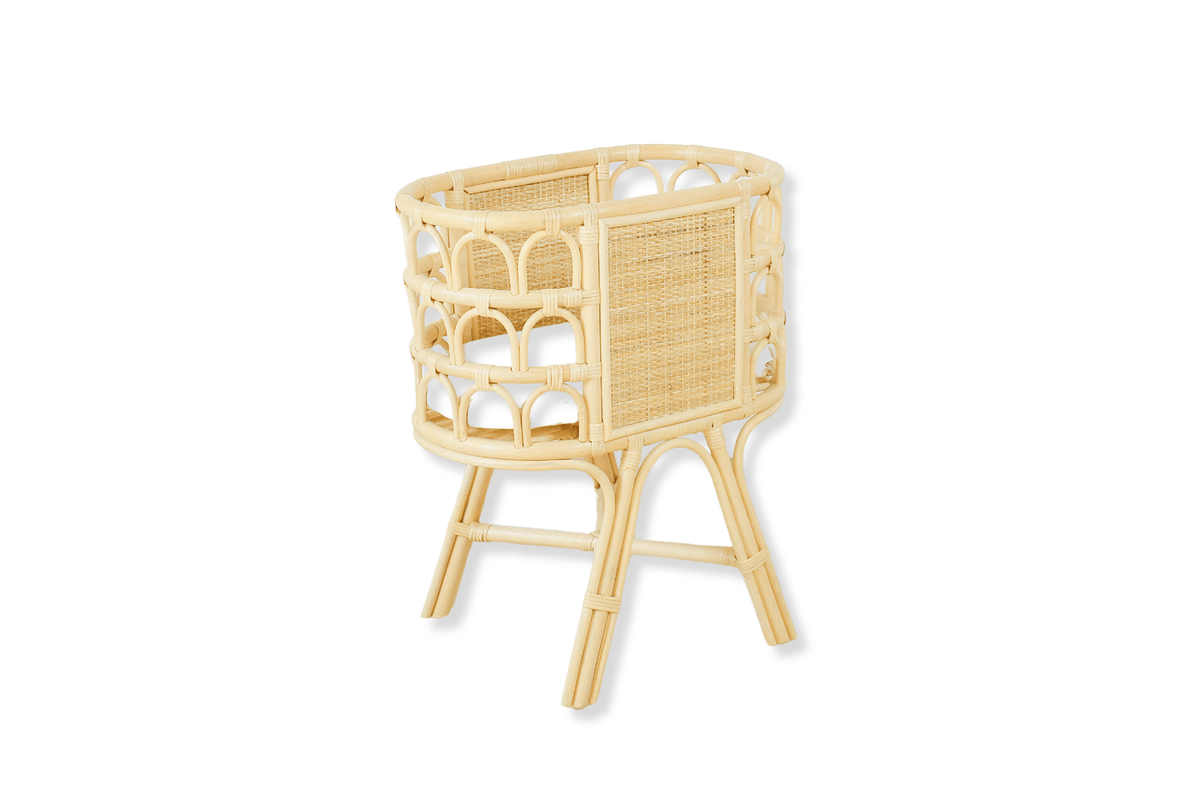 Natural rattan doll crib with raised legs, woven panels, and open arched sides