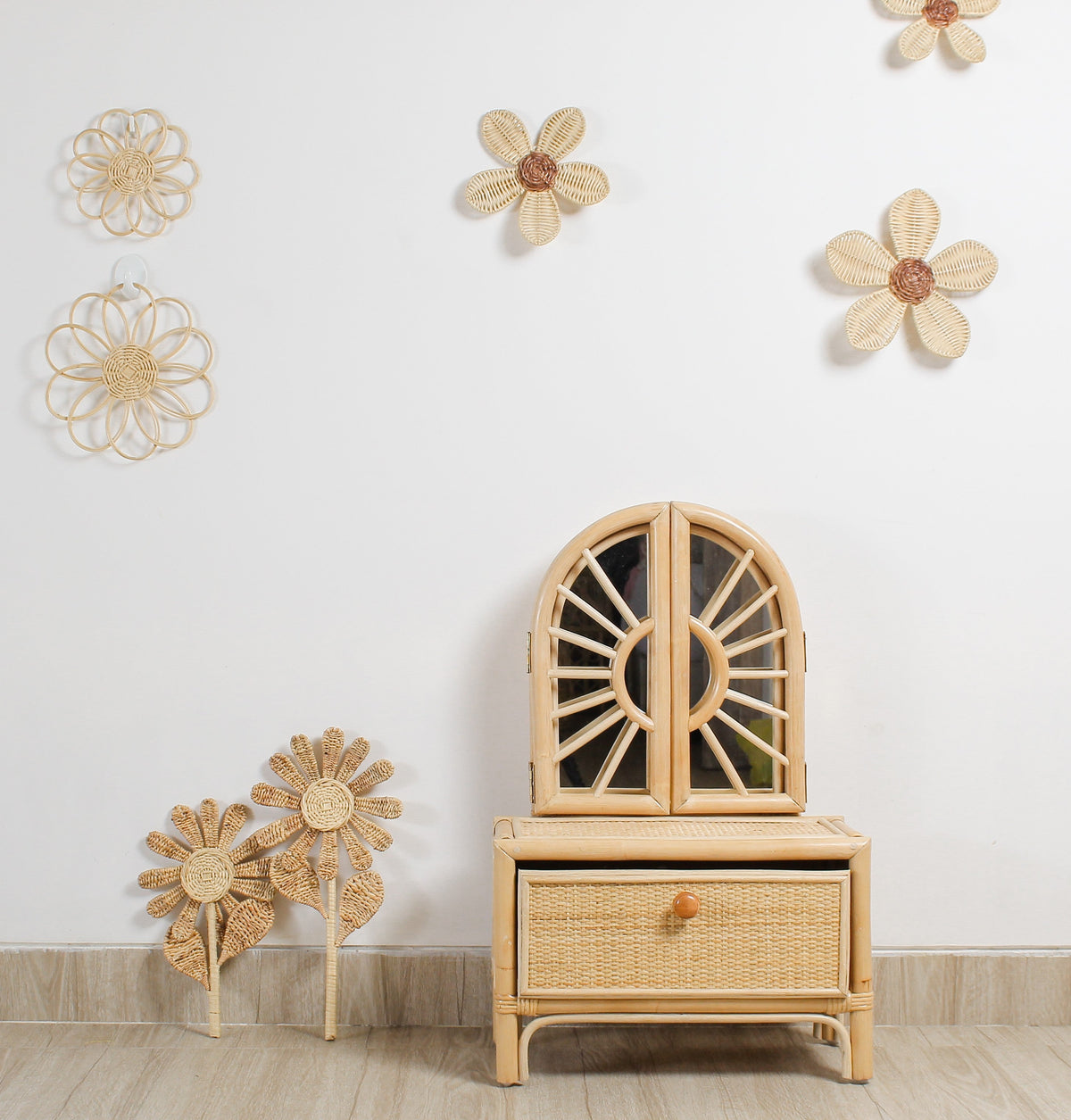 Woven rattan flower stems displayed against a wall beside a cabinet