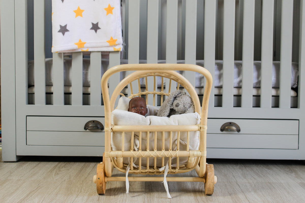 Front view of rattan doll stroller with white bedding and two dolls