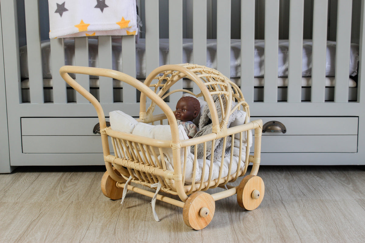 Natural rattan doll pram with a woven hood, curved handle, and wooden wheels