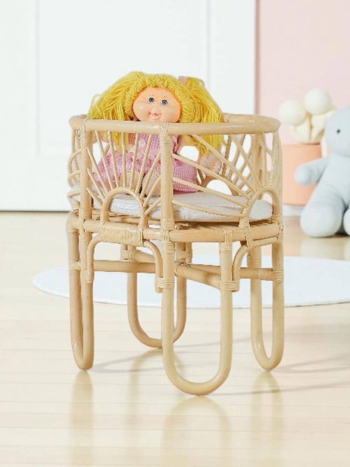 Toy doll crib with a woven frame and a doll inside
