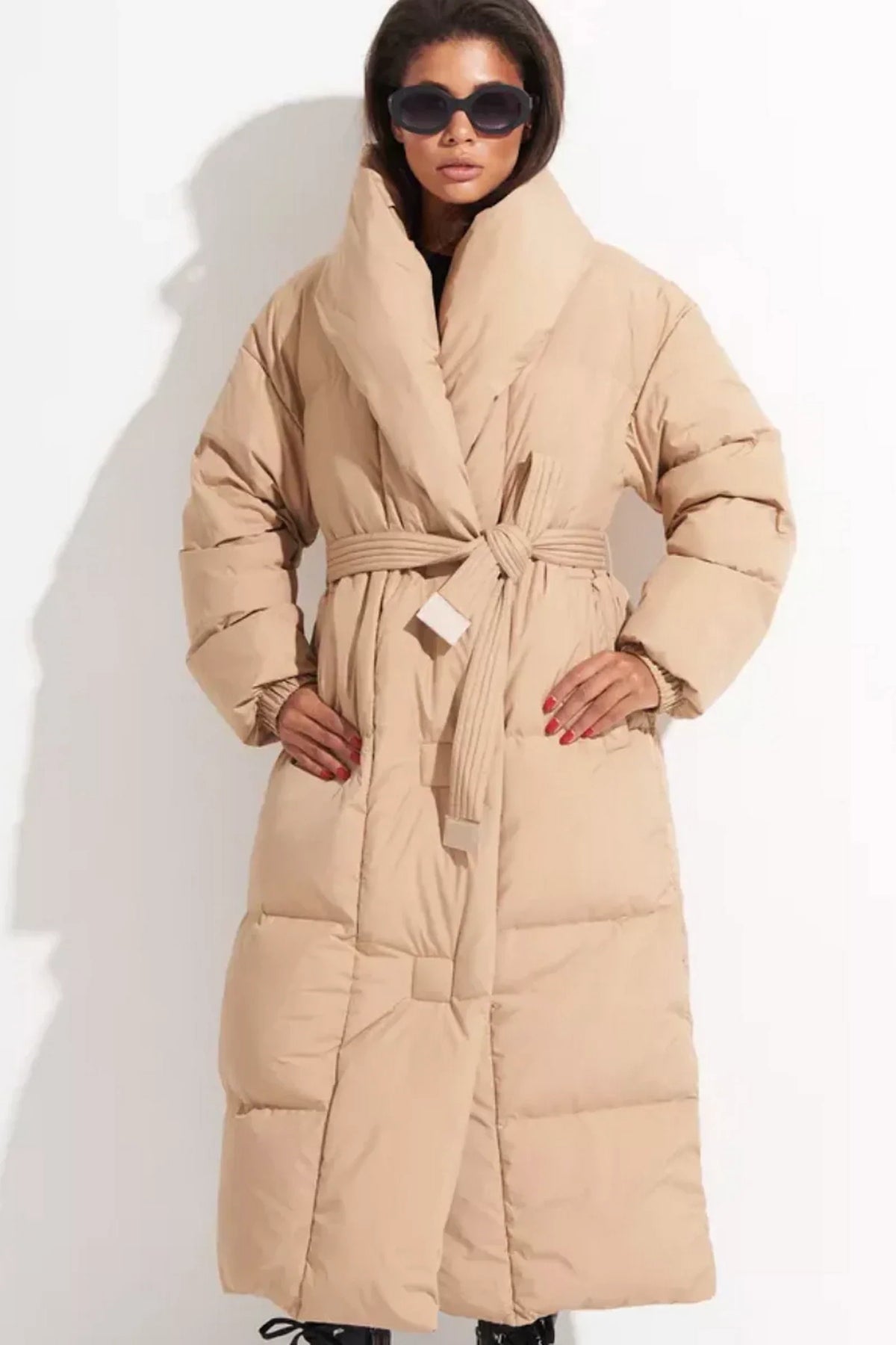 Front view of a long quilted down coat with a wide collar and matching tie belt.