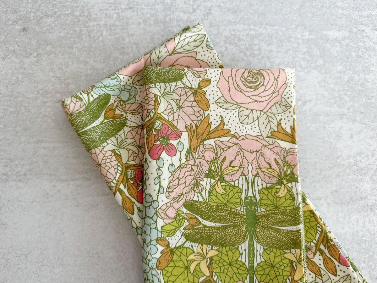 Floral dragonfly cloth napkins, folded squares with pink roses and green foliage pattern