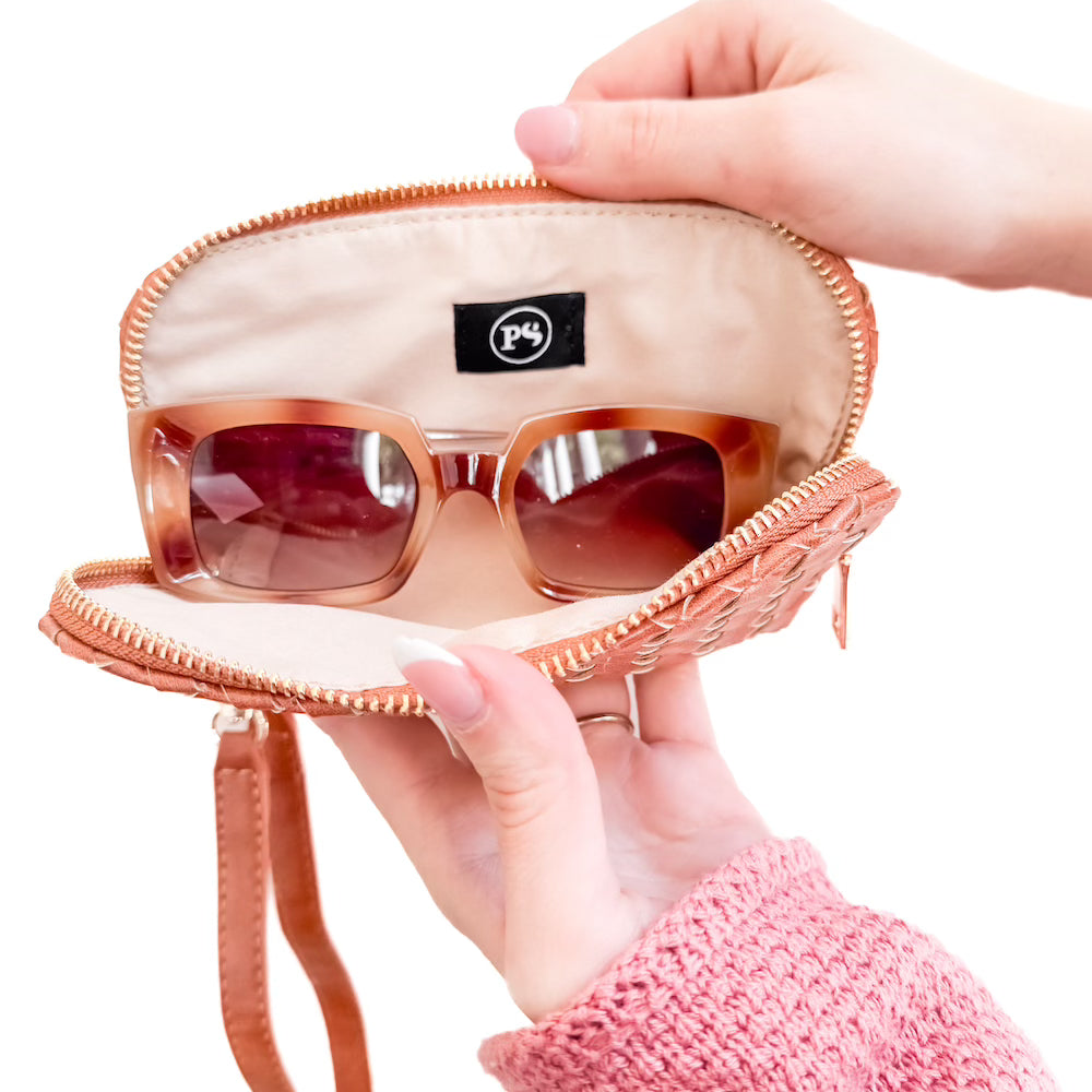 Braided sunglass case wristlet, open zip showing amber frames and logo patch