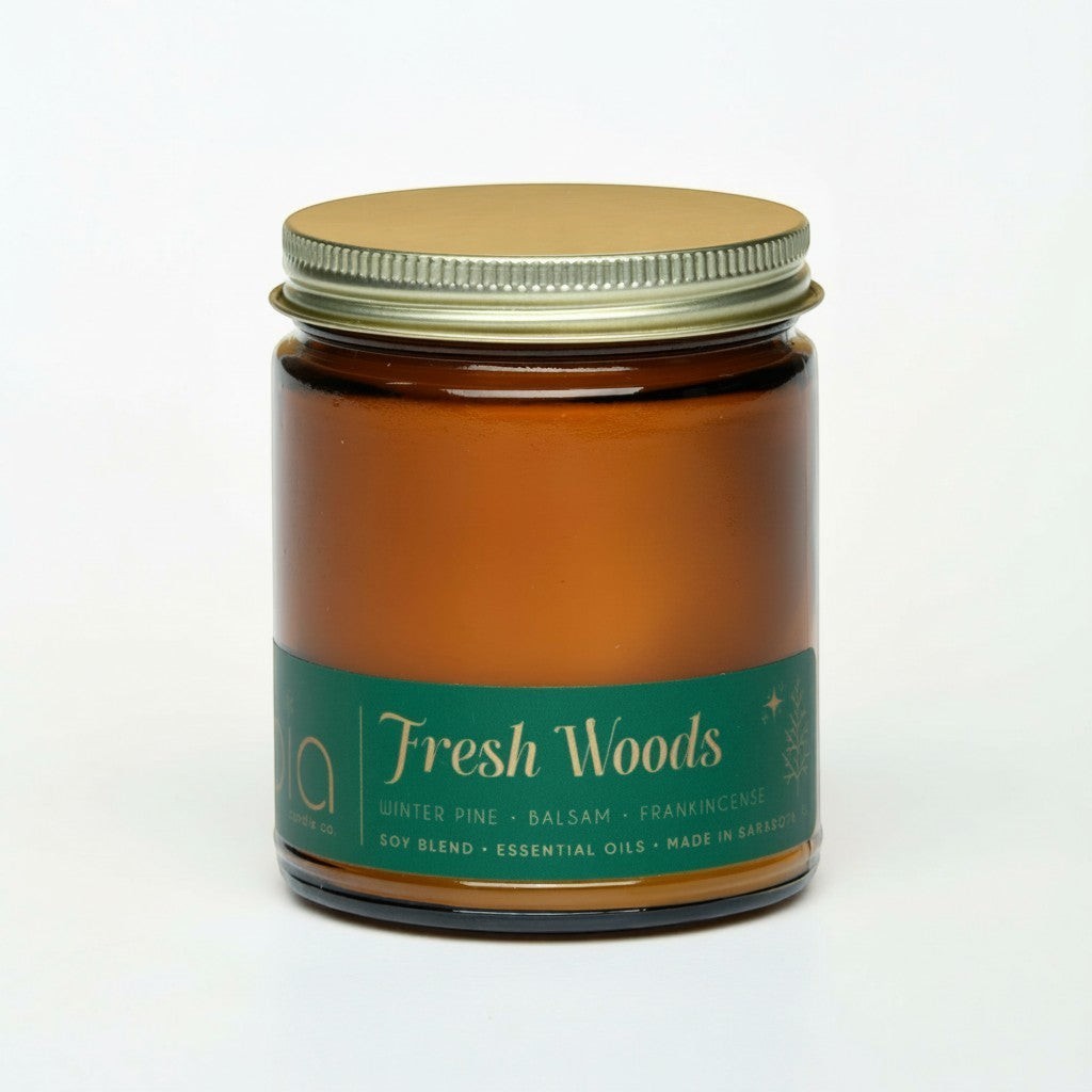 Amber glass candle jar with green Fresh Woods label and metal lid