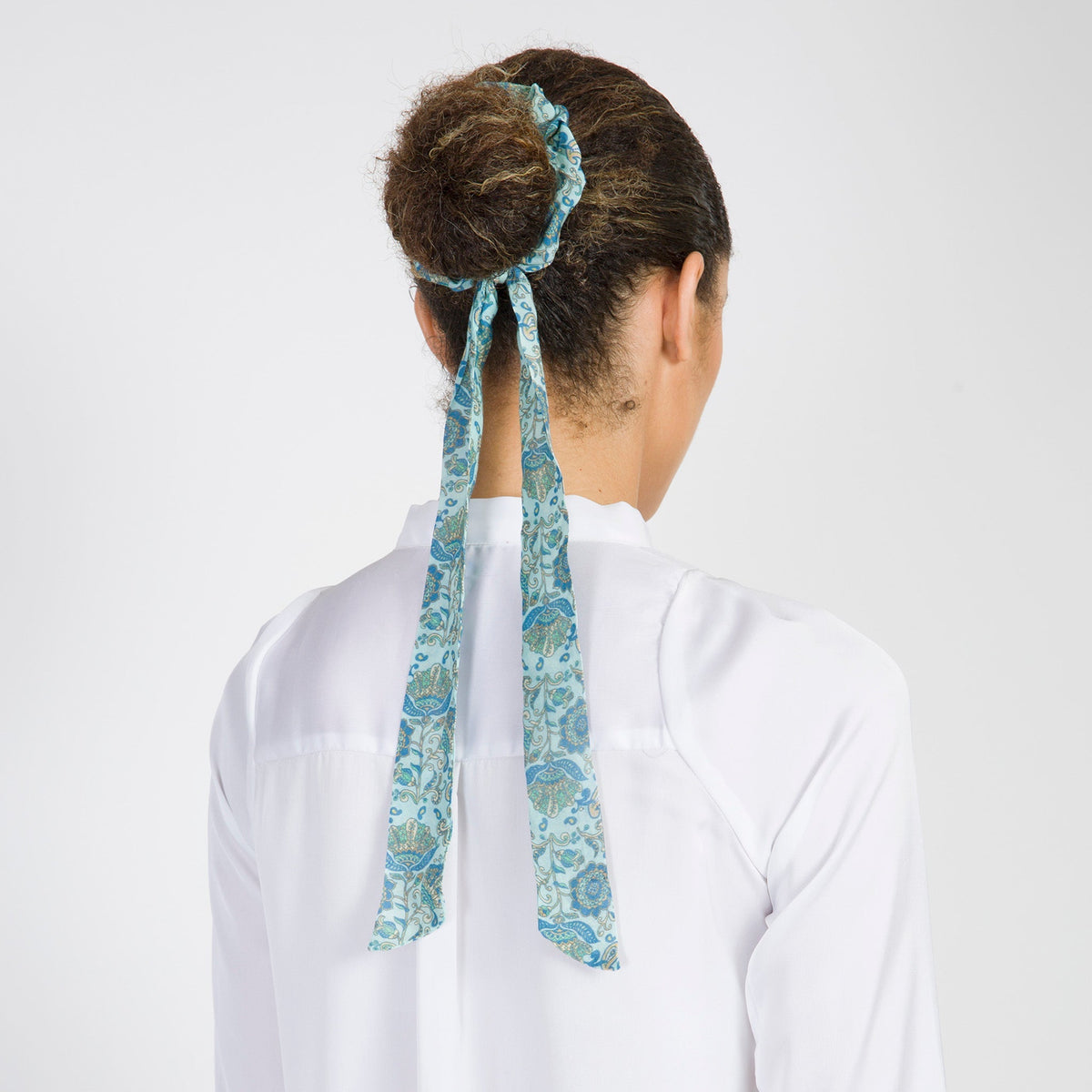Hair scarf worn at back of head: turquoise paisley ribbon tied in a bow