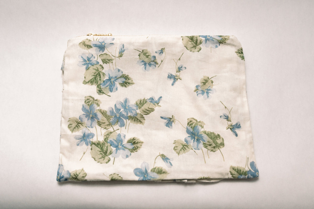 Cream floral zipper pouch with blue and green botanical print, gathered top and zipper
