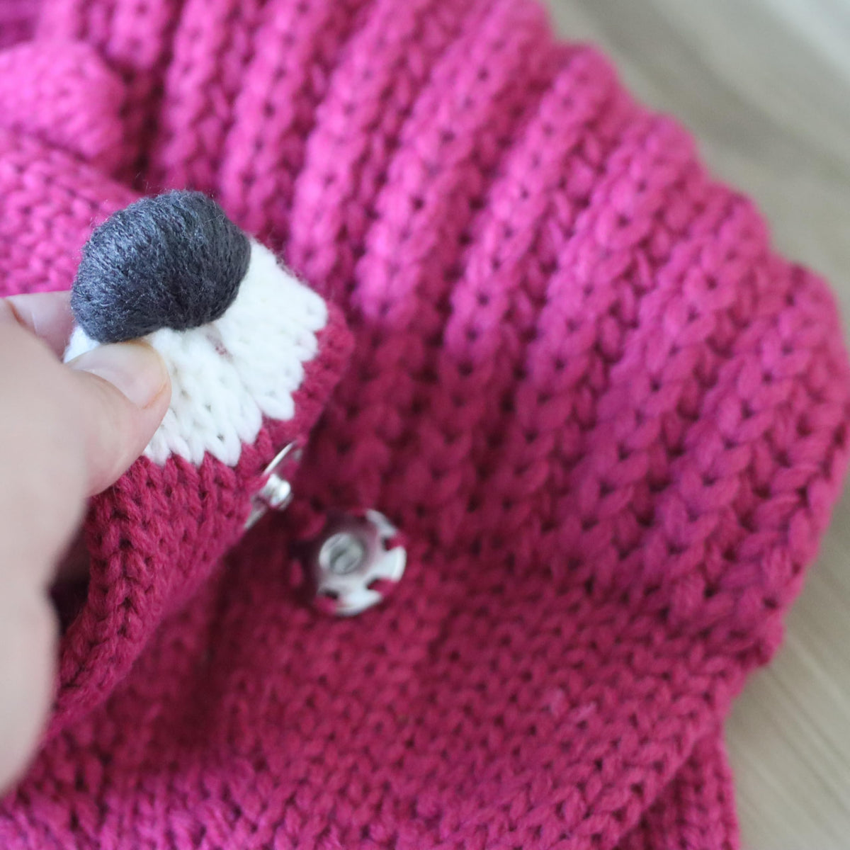 Close-up of the pink knitted fox neck warmer's snap button and fox nose detail