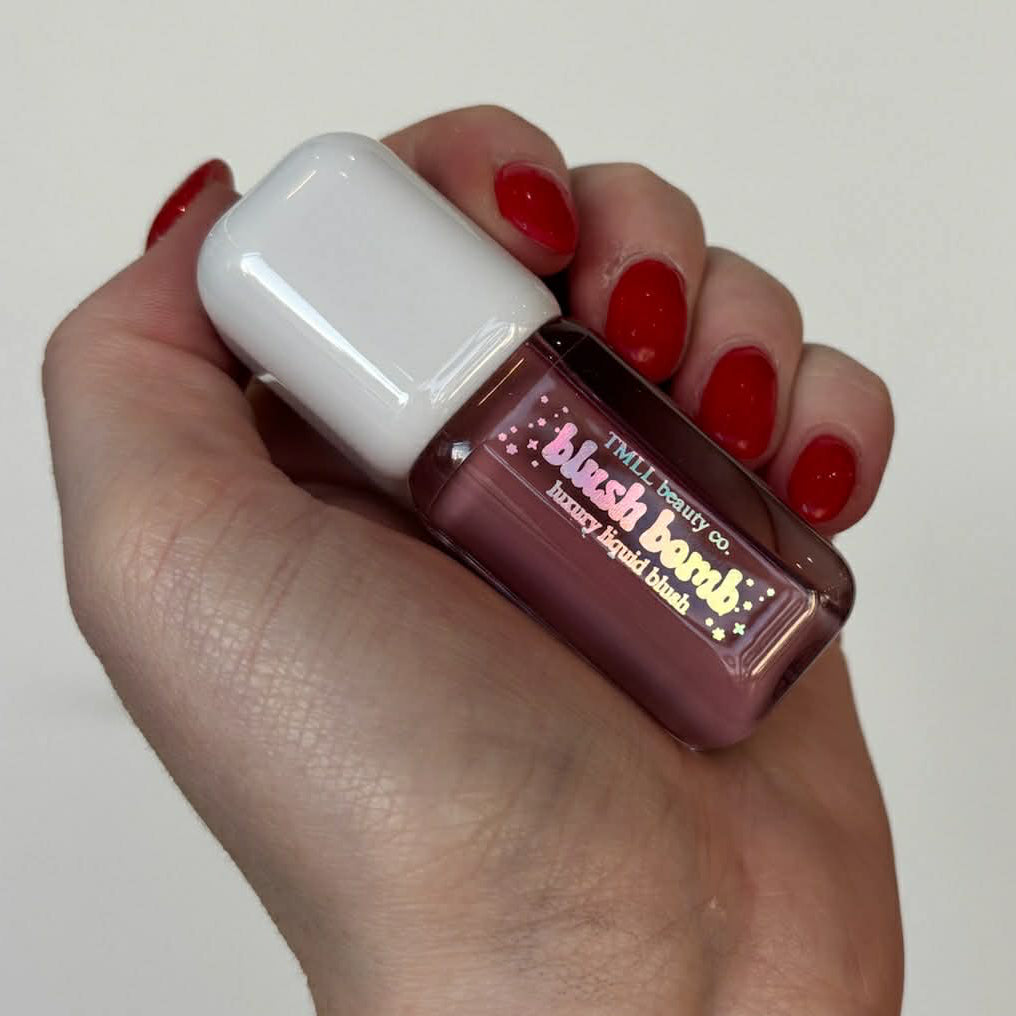 Blush Bom liquid blush bottle with white cap, held in hand