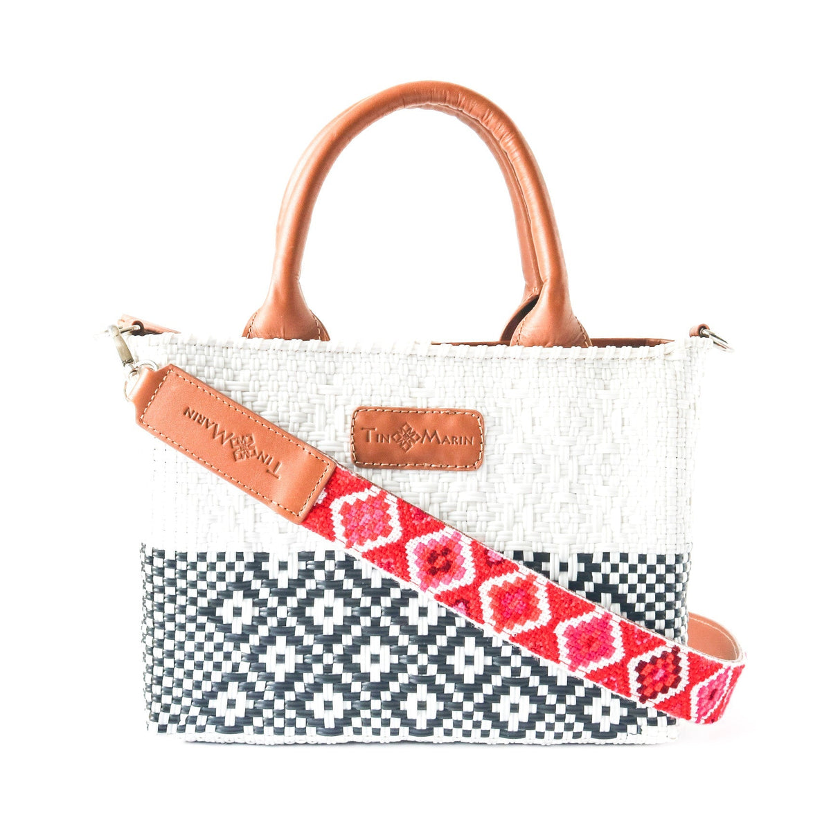Small woven crossbody bag with tan leather handles, black pattern, and red embroidered strap