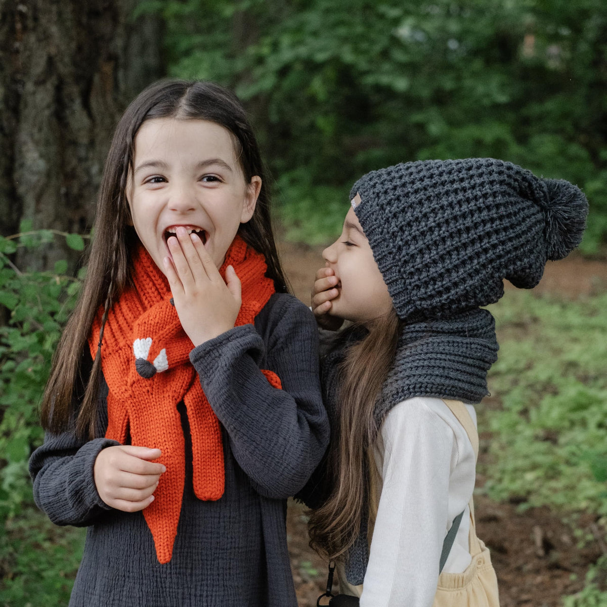 Orange knitted fox neck warmer worn by a child, with fox face detail and long ends