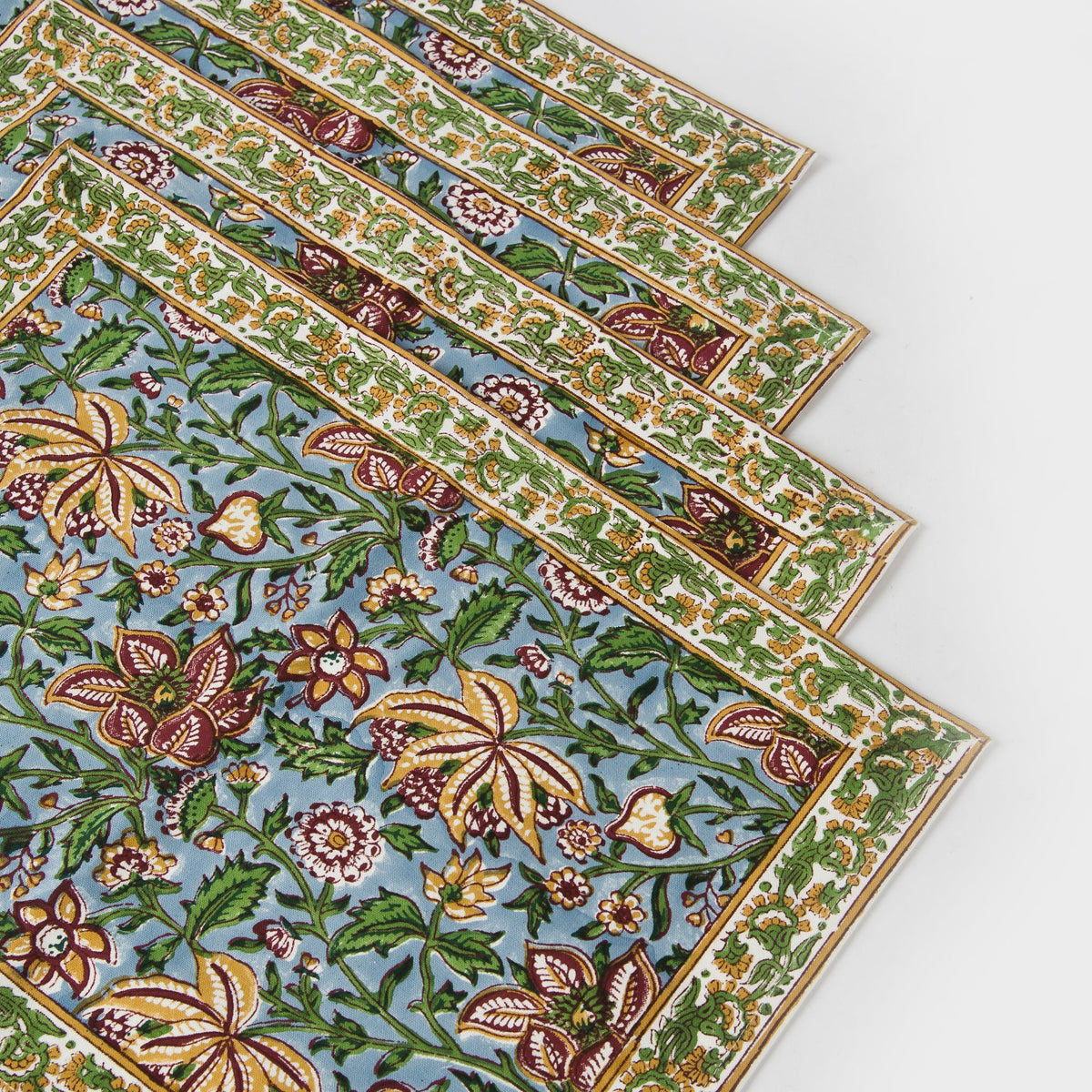 Hand-block printed cotton placemats in green and blue floral motifs with ornate border