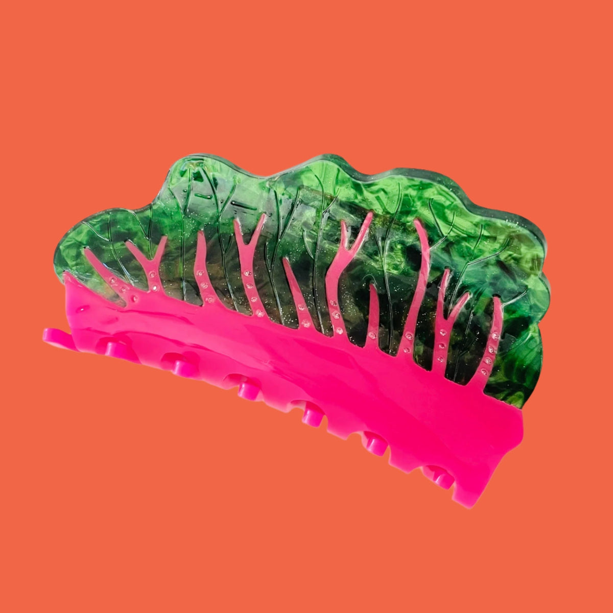 Green translucent hair claw with pink underside and comb teeth