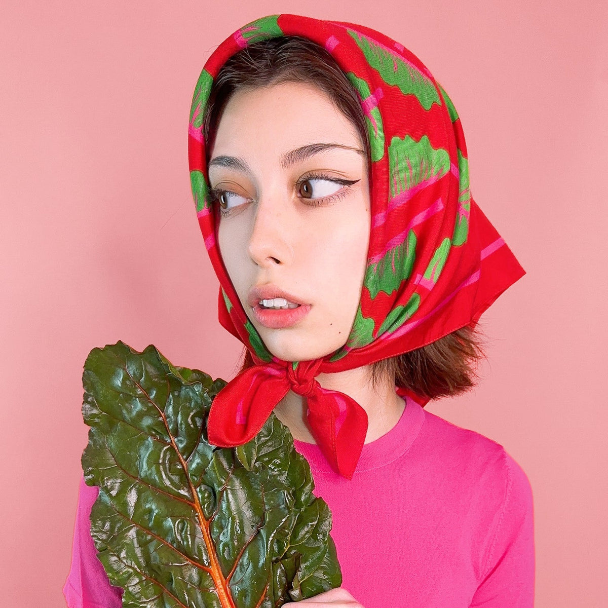 Red bandana headscarf with green chard leaf pattern, tied under chin