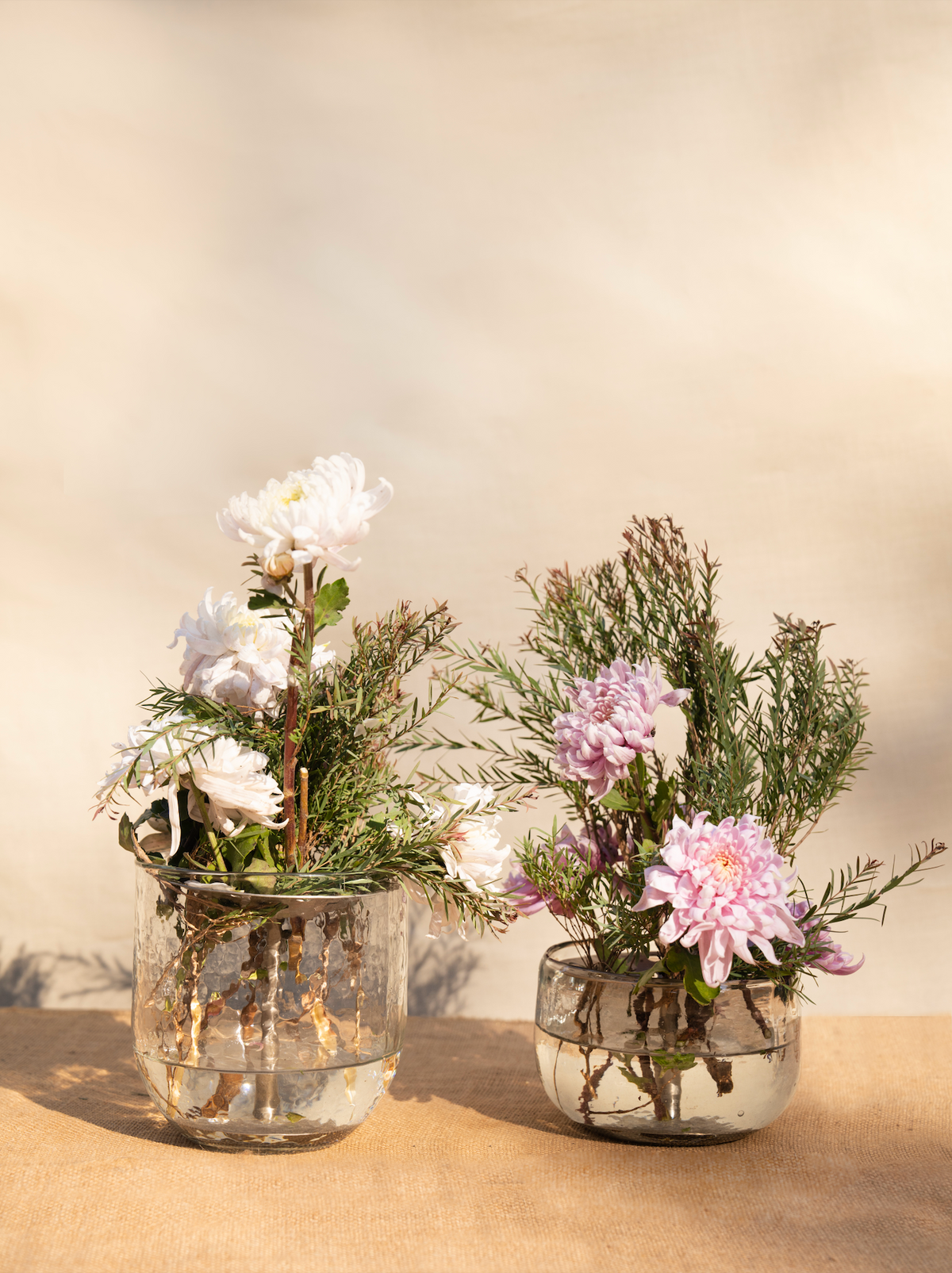 Pair of low glass vases with metal flower frog holding white and pink flowers