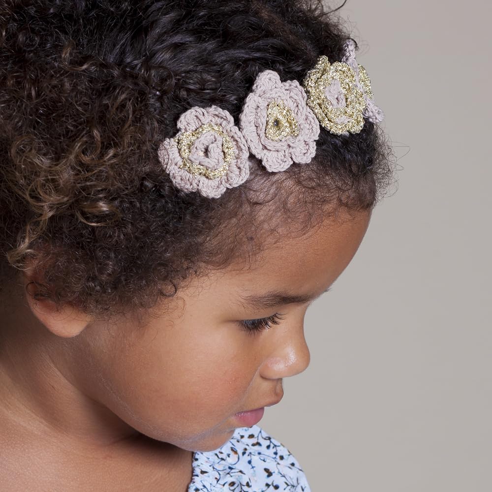 Pale pink and gold knitted flower headband worn by a child