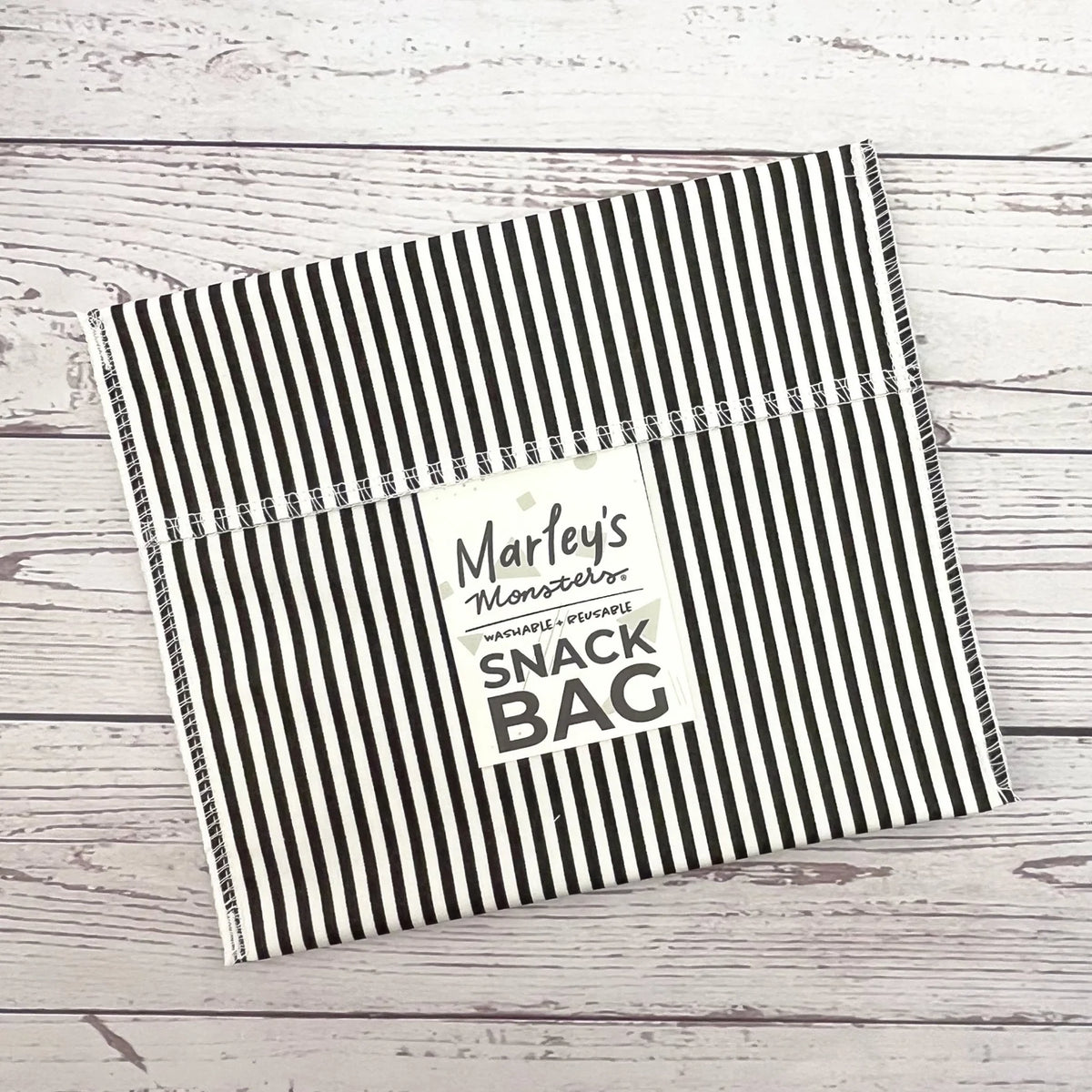 Reusable snack bag with black-and-white vertical stripes on white fabric, sealed top flap.