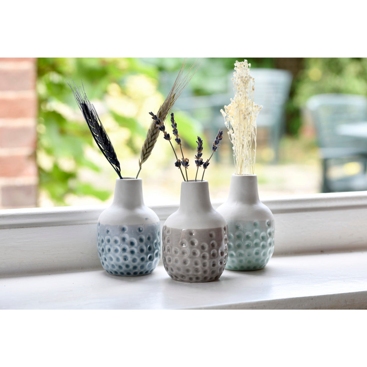 Three mini ceramic dot vases on windowsill, speckled light blue, gray and mint
