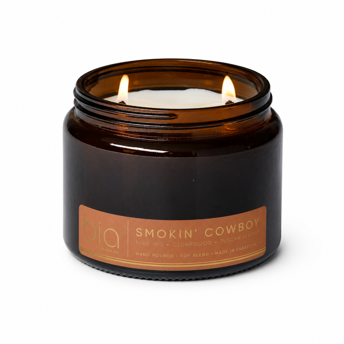 Amber glass candle jar with 'Smokin' Cowboy' label and two wicks burning