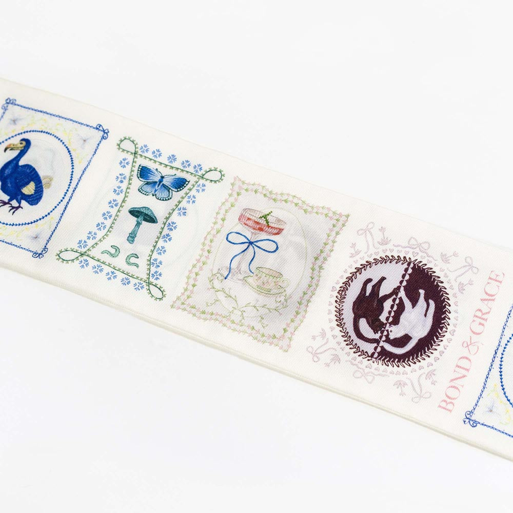 Silk twilly scarf close-up with playing-card blocks, butterfly icon, and BOND & GRACE text