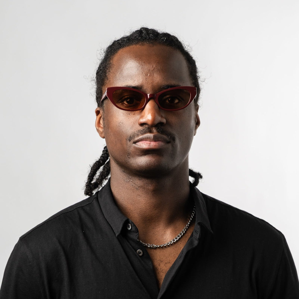 Model wearing burgundy cat-eye sunglasses with amber tinted lenses