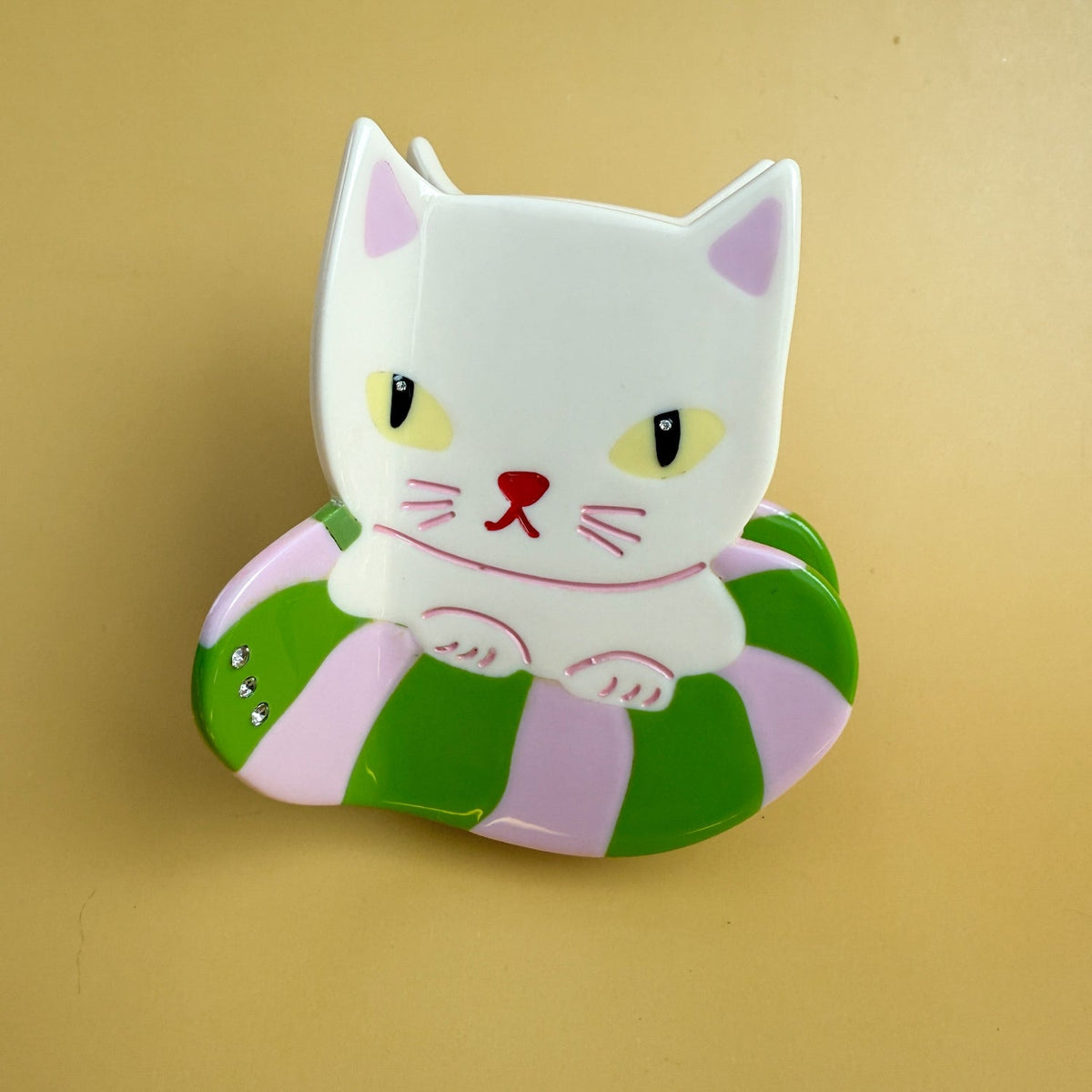 Cat hair claw clip featuring white cat face with green-and-pink swirl details