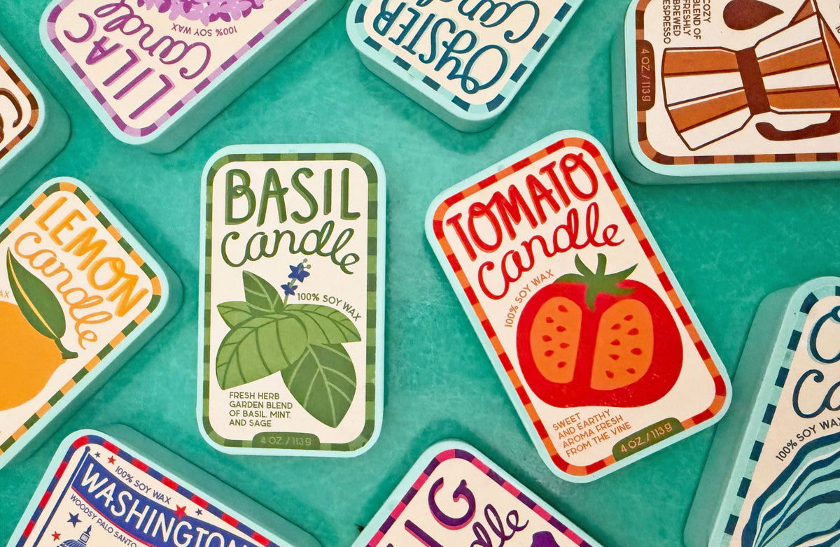Assorted soy candle tins on a tray, including Basil and Tomato labels.