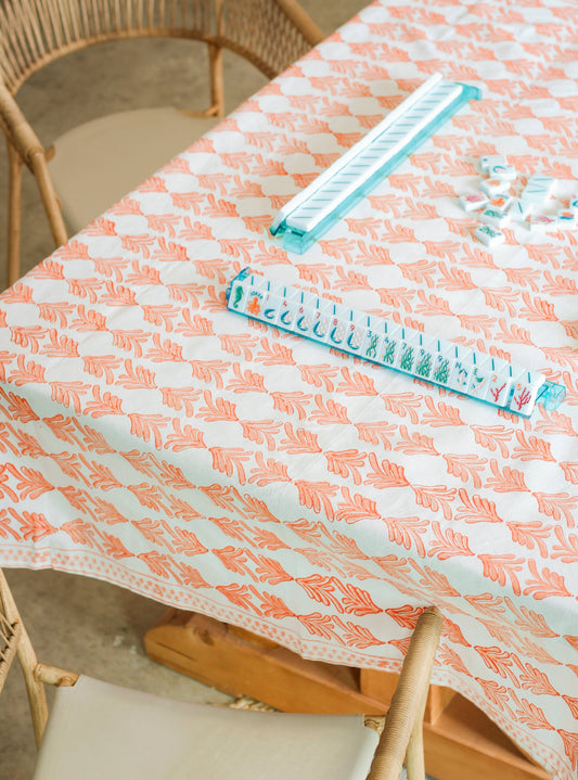 Orange-and-white table throw with repeating leaf print, spread across a table