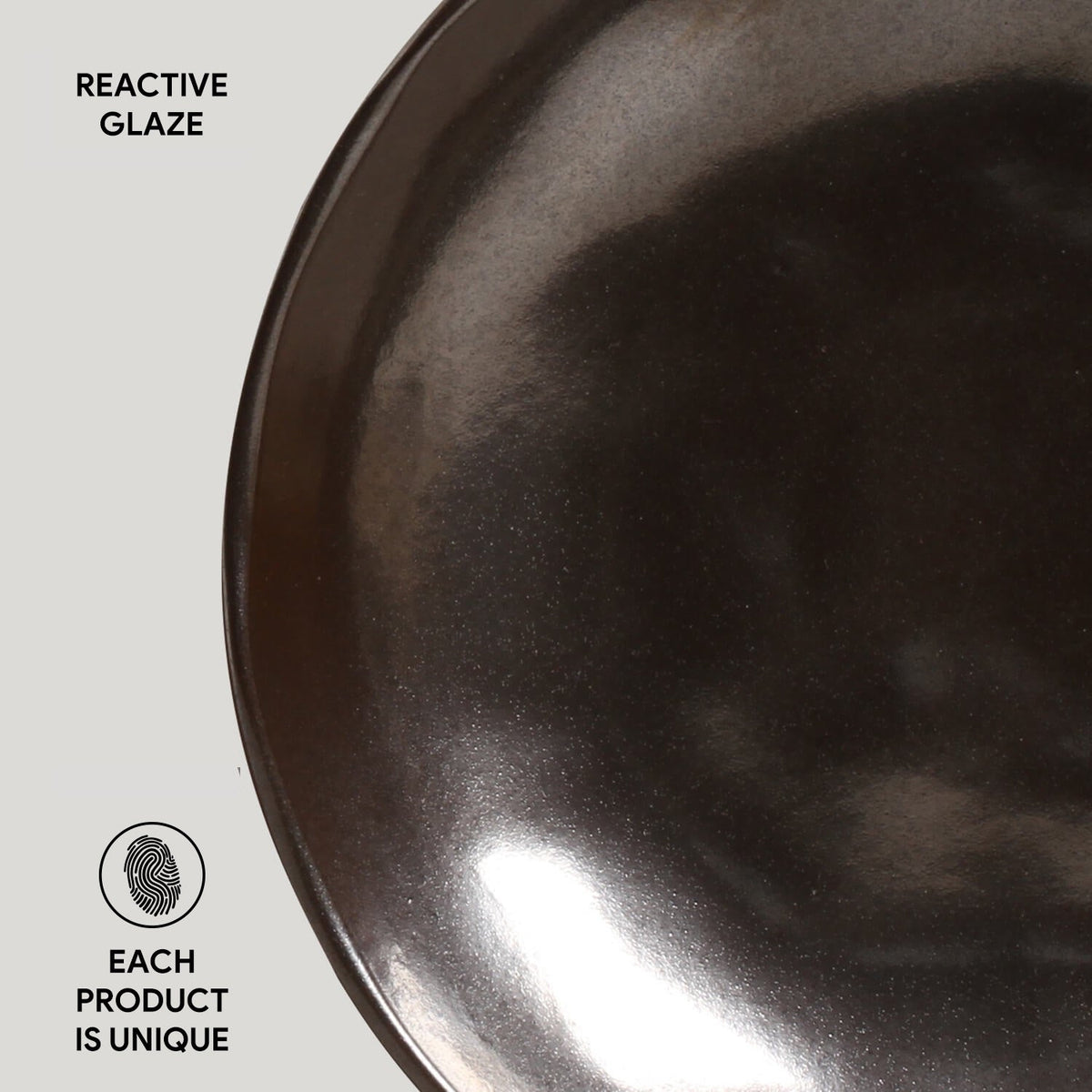 Dark reactive-glaze ceramic pasta plate, glossy interior with speckled texture and rim.