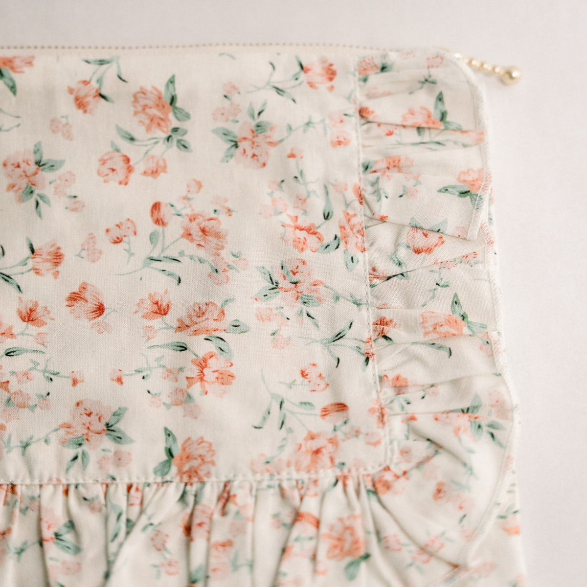 Floral ruffle zipper pouch close-up with layered ruffle trim and zipper top.