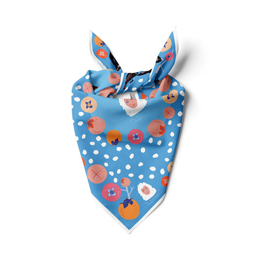 Blue bandana folded into triangle with knot, featuring white dots and animal fruit prints