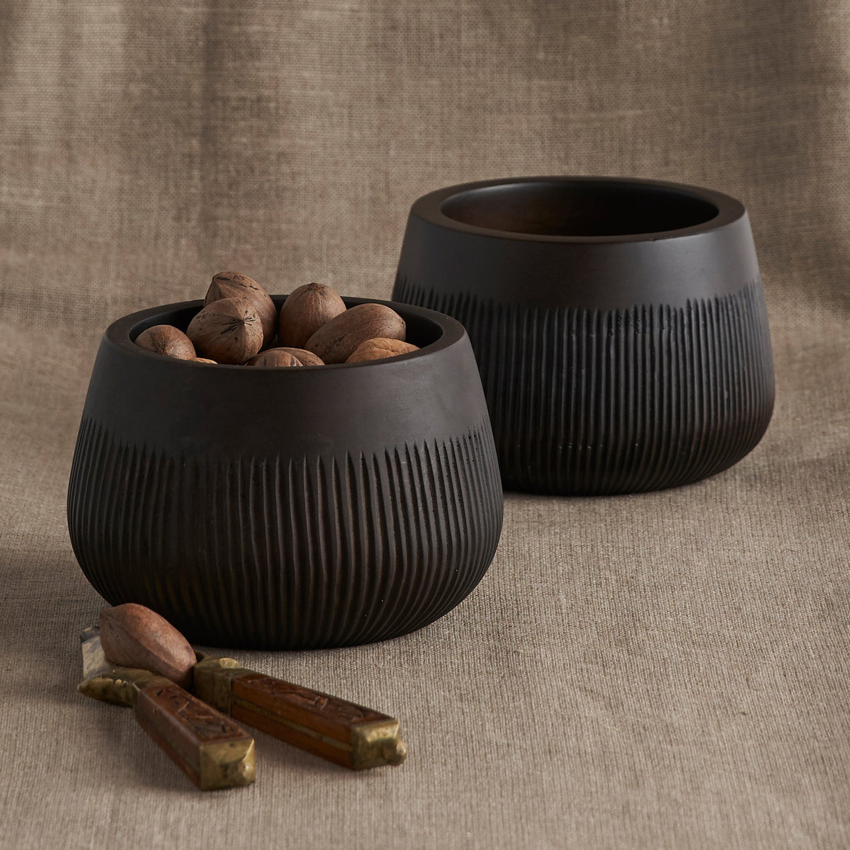 Dark ridged ceramic bowl with wide fluted sides, filled with small ornaments