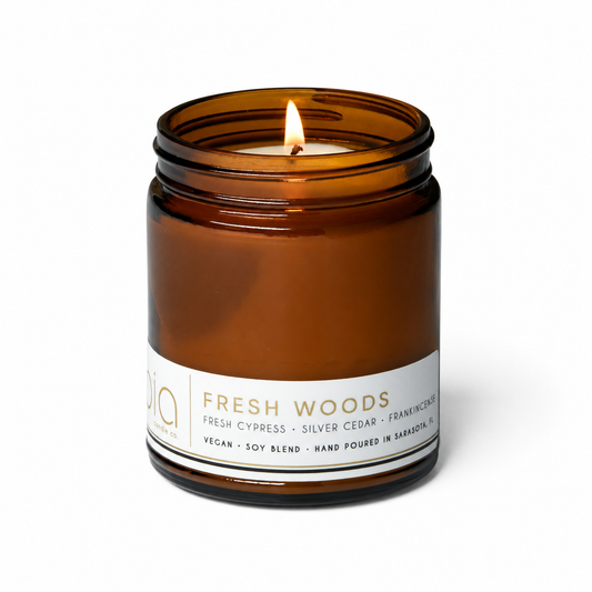 Amber glass soy blend candle jar with a centered flame, white brand label around base.