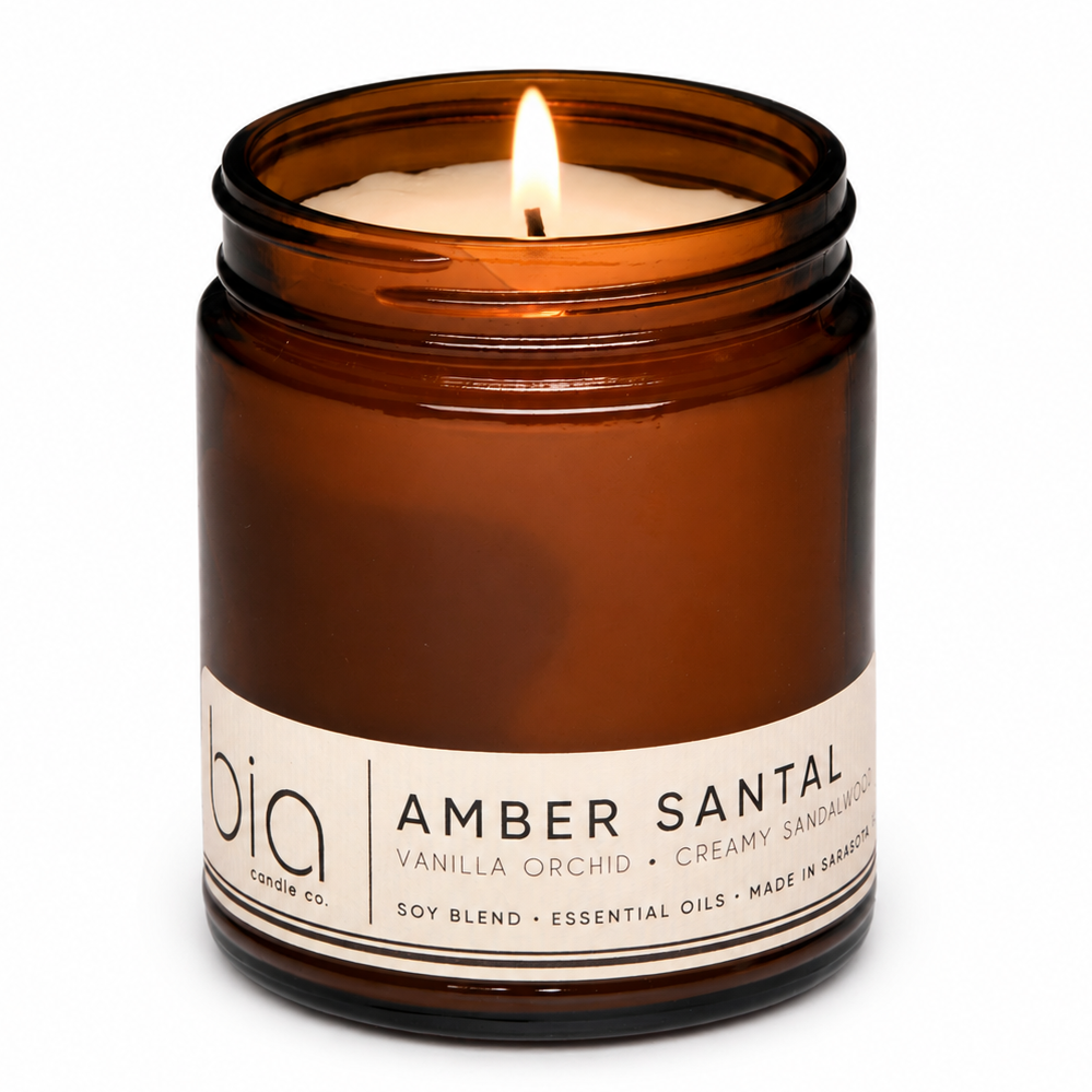 Amber glass soy candle jar with single flame and printed label, centered view