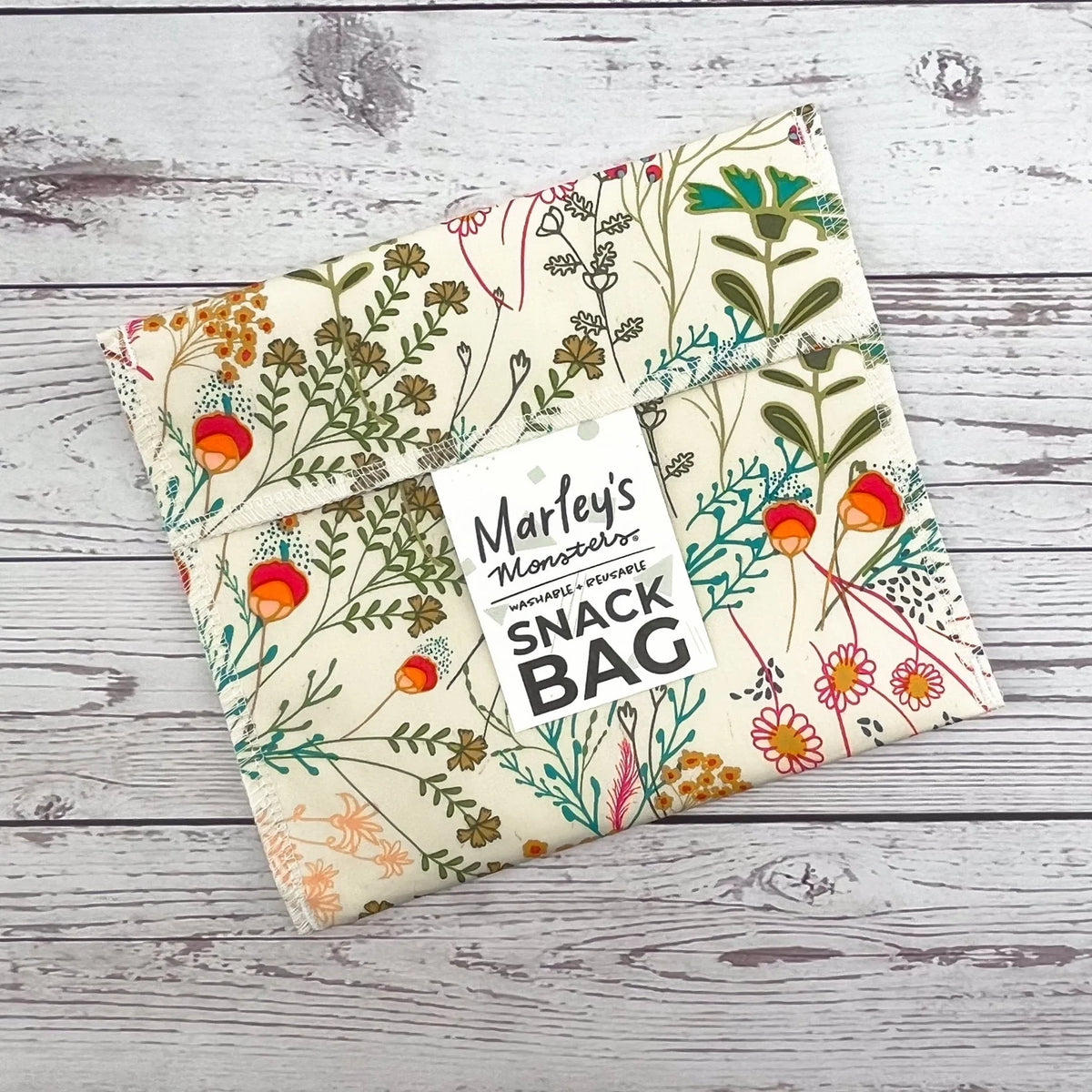 Reusable snack bag with botanical floral print on cream fabric, sealed top closure flap.