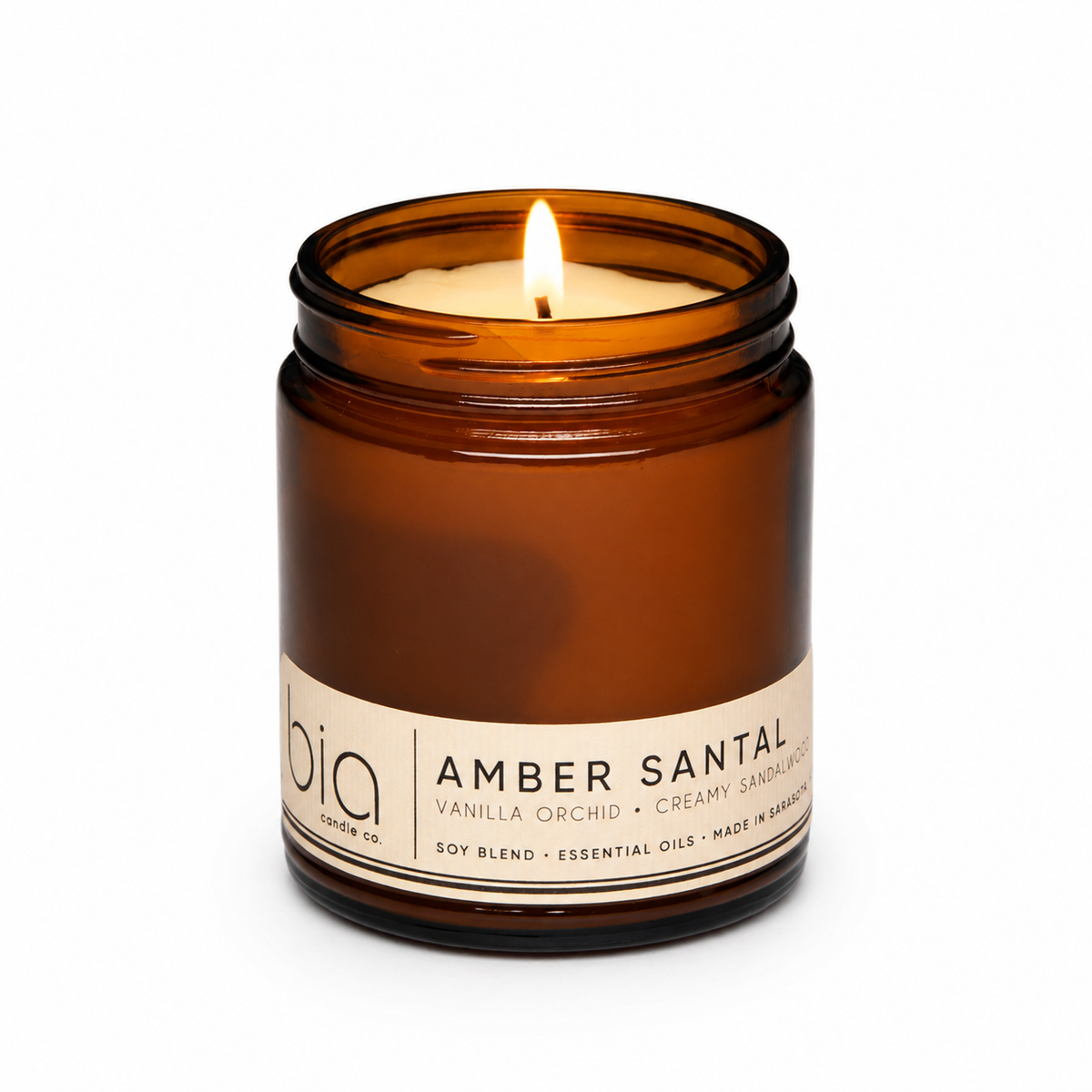 Amber soy blend candle in amber glass jar with central flame and front label
