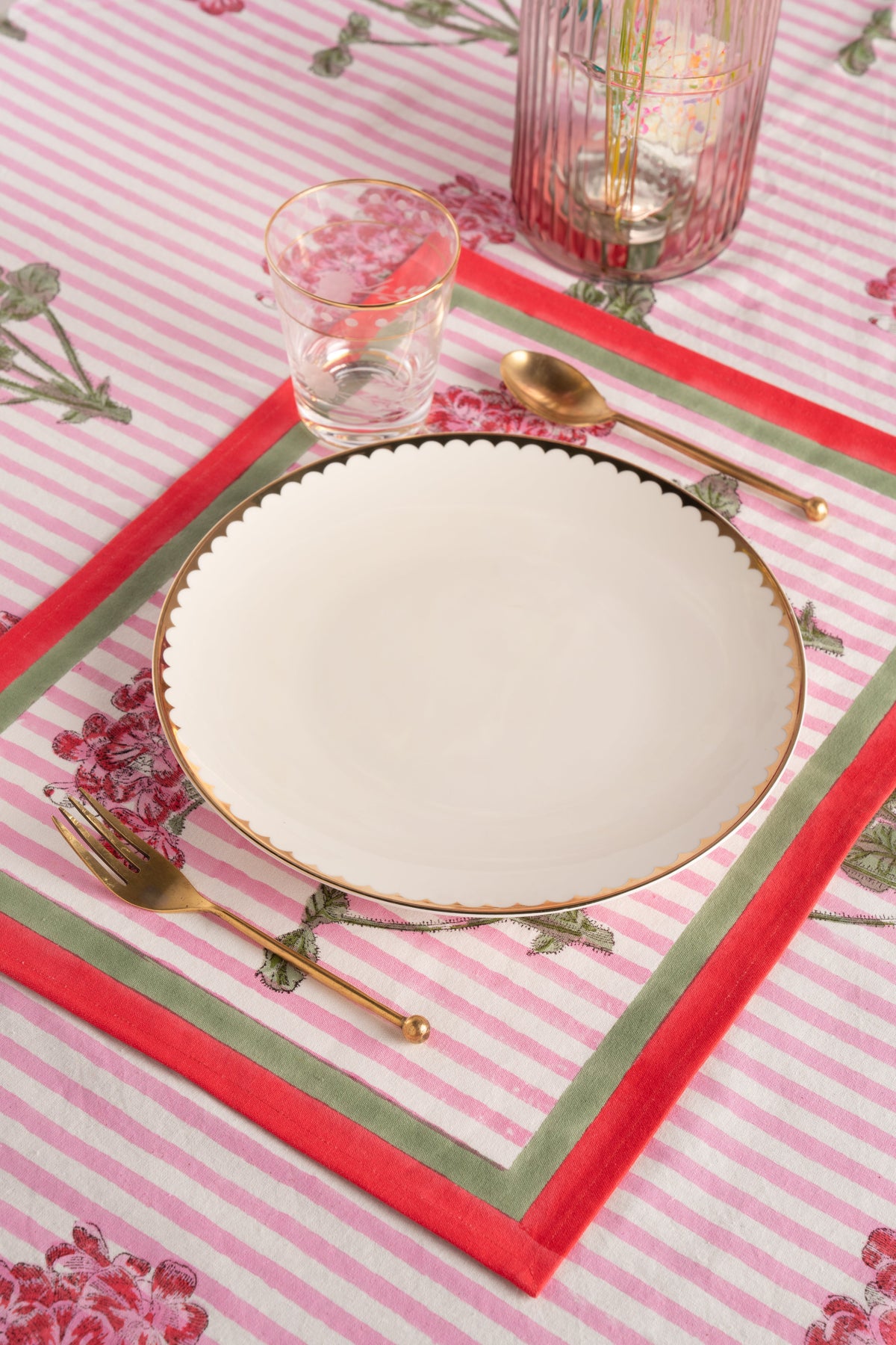 Pink striped placemat with hydrangea floral accents, scalloped plate edge and red border