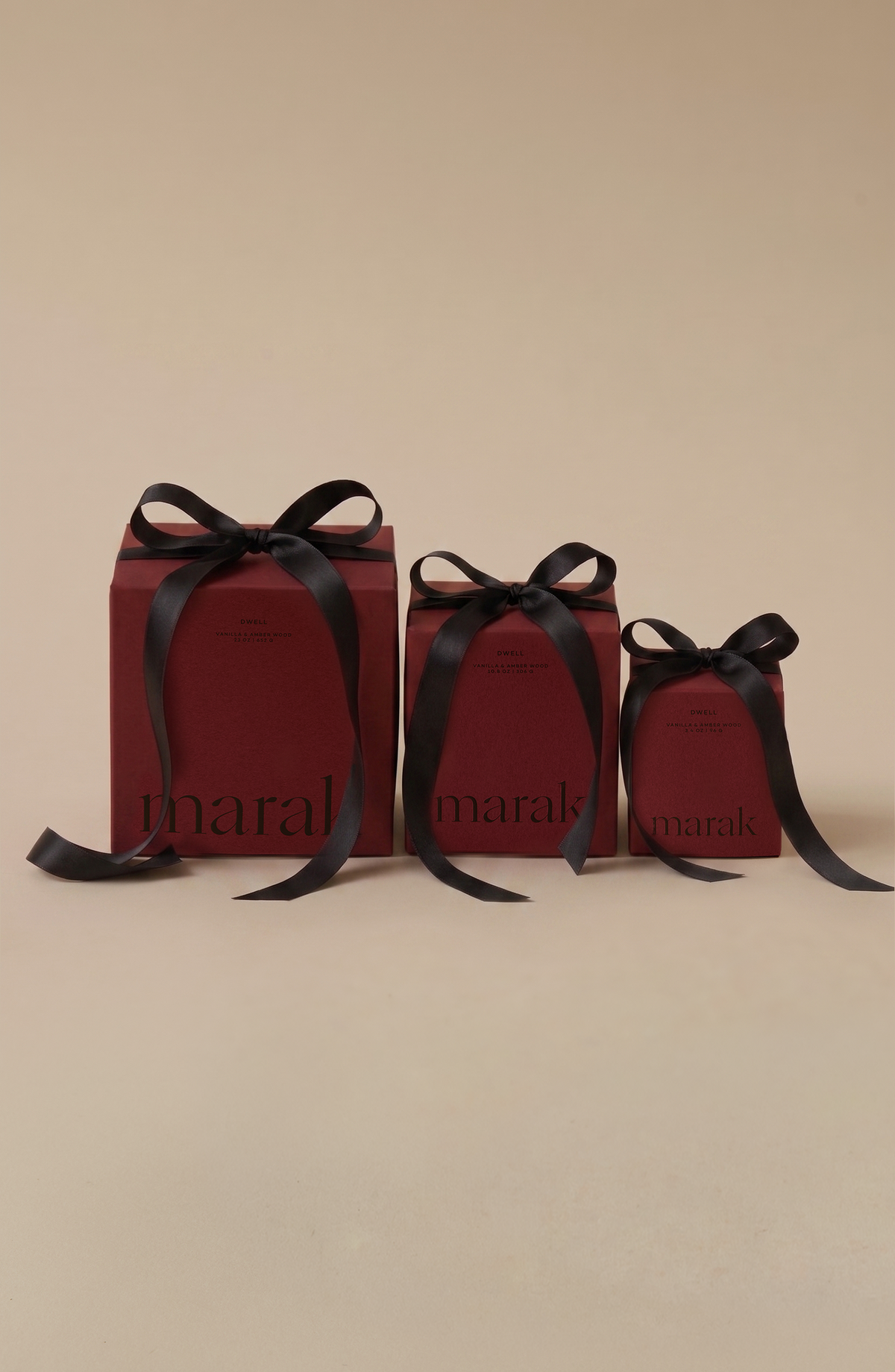 Gift candle set of Dwell Vanilla & Amber Wood: three maroon marak boxes with black bows