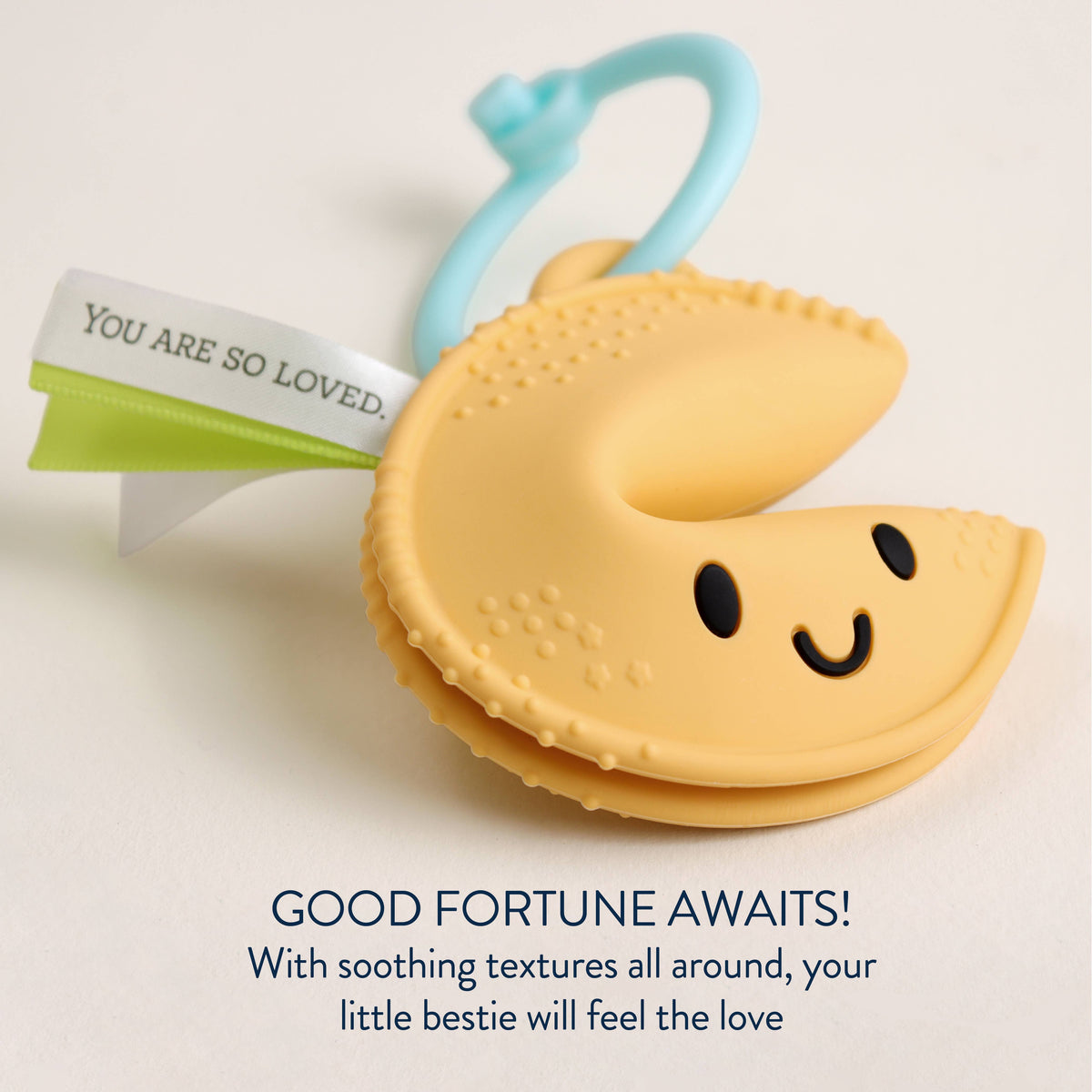 Yellow fortune-cookie silicone teether with blue ring and green ribbon detail