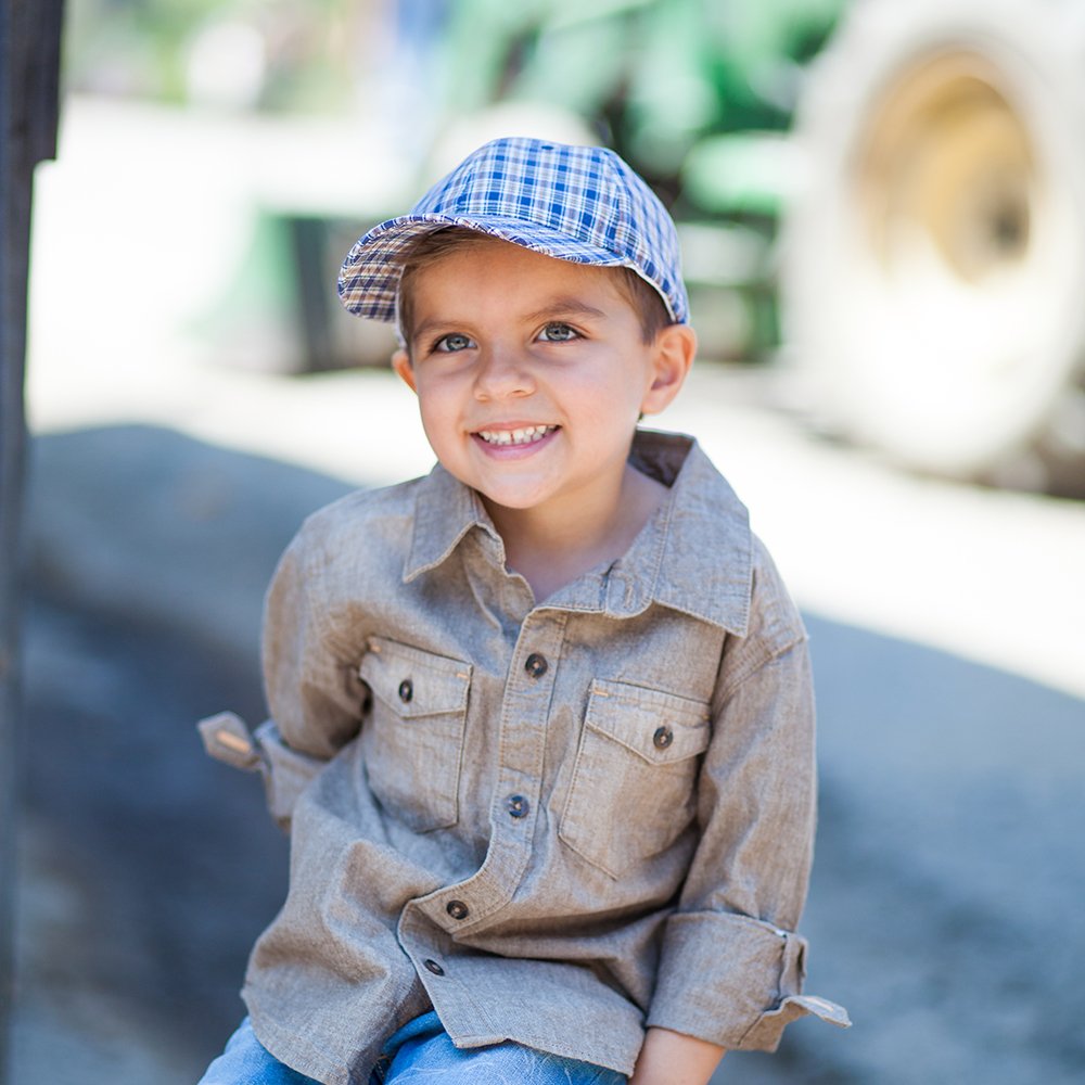 Child wearing a blue plaid baseball cap with a curved brim
