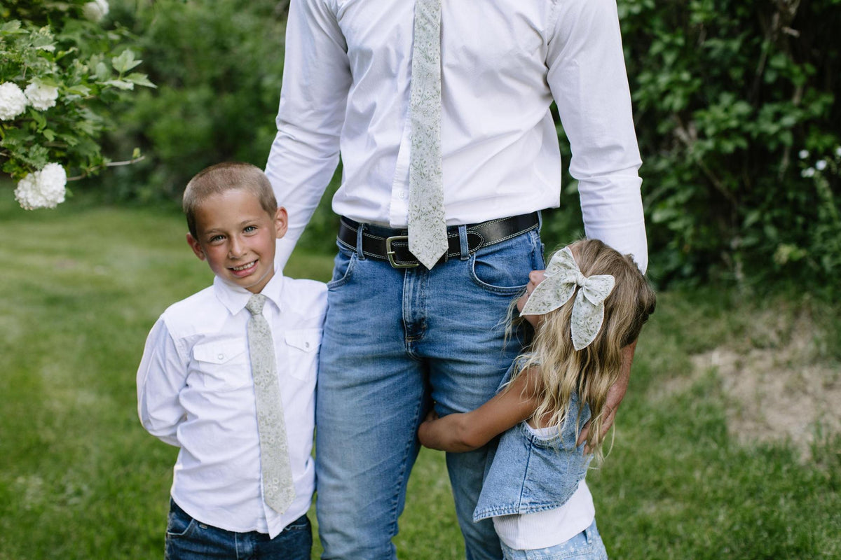 Light floral boys necktie with subtle pattern, worn with a button-up shirt.