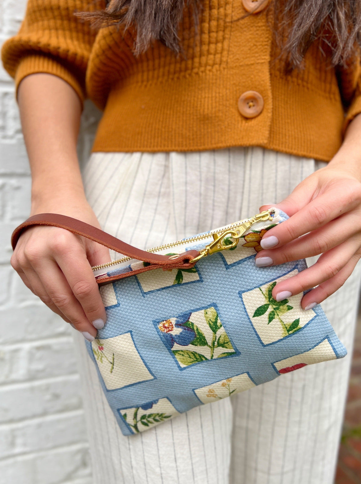 Blue floral patchwork wristlet purse with gold zipper and brown wrist strap