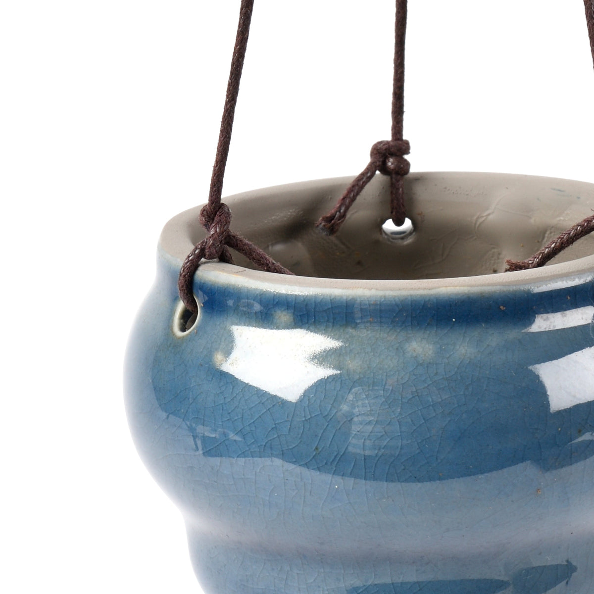 Close-up of a blue hanging ceramic vase planter rim with brown cords