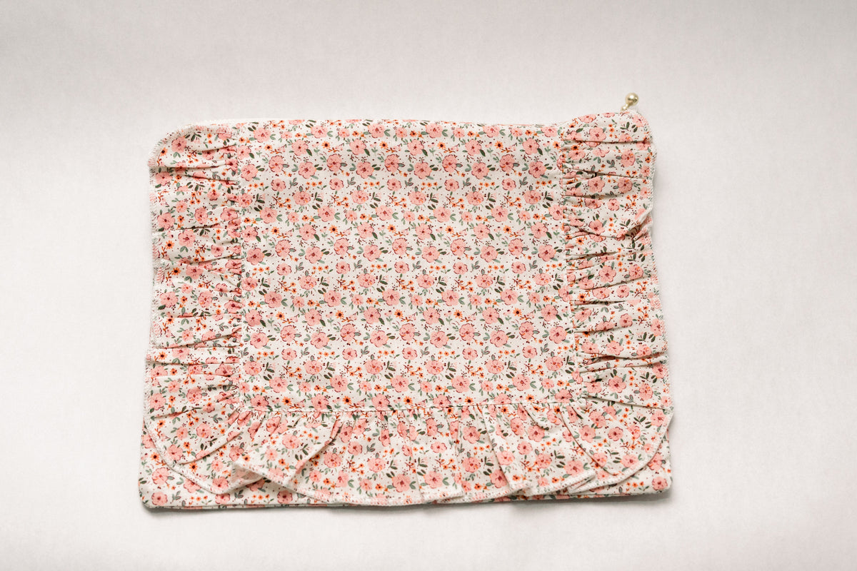 Peach floral ruffle zipper pouch with gold zipper pull and gathered ruffle edge