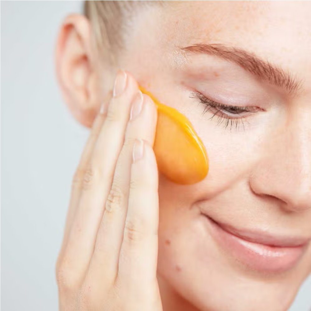 Orange cleansing butter applied under-eye area on smiling face
