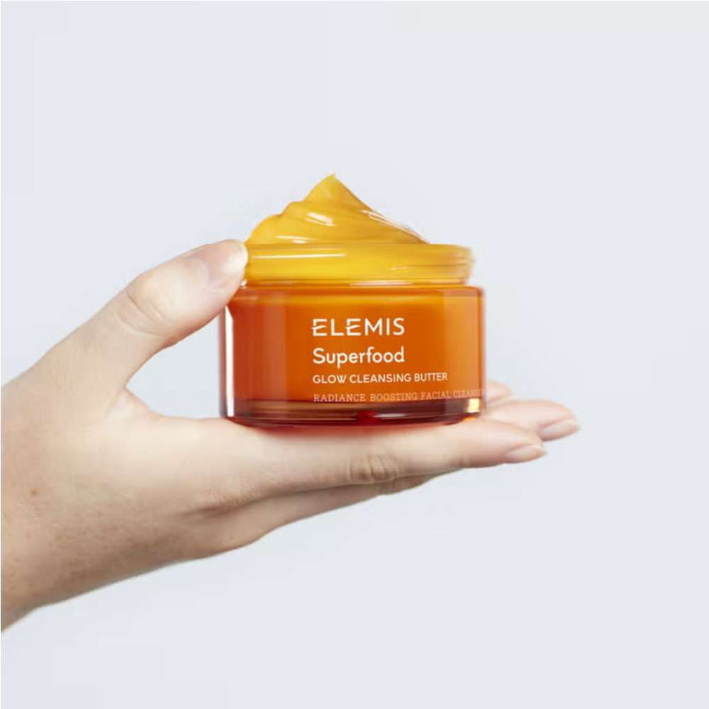 Elemis cleansing butter jar held in hands, orange glass with yellow cap