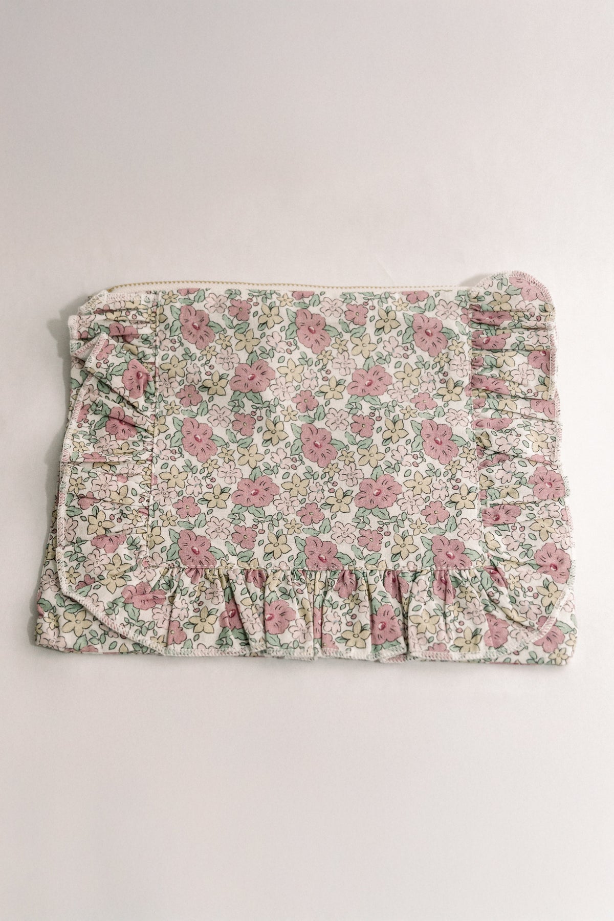 Floral ruffle zipper pouch with pink and green flowers on light cream fabric.