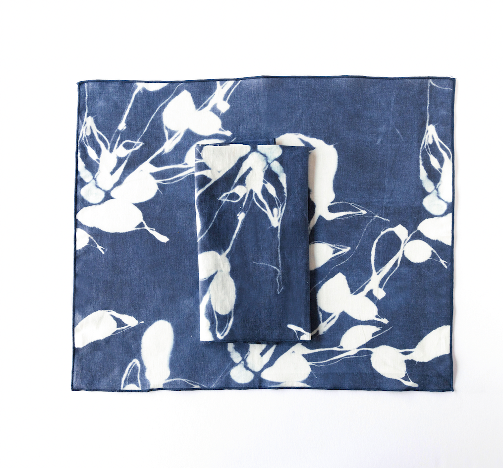 Layered indigo placemats with white bird-and-flower print, rectangular set
