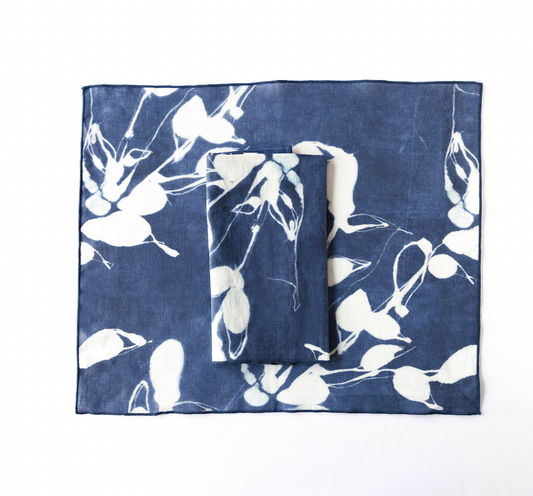 Layered indigo placemats with white bird-and-flower print, rectangular set