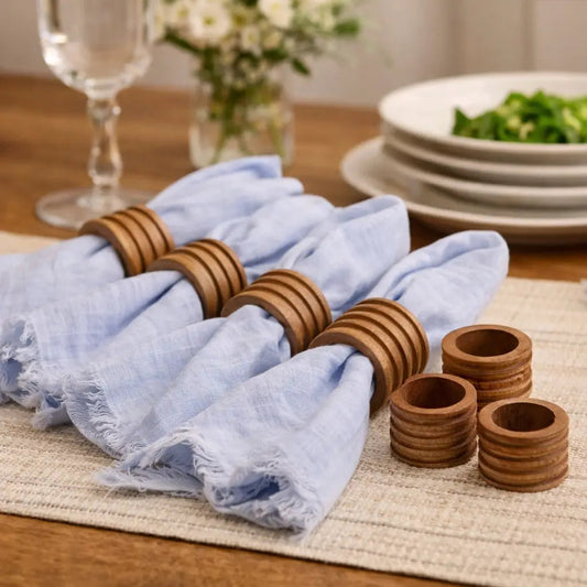 Set of 4 wooden napkin rings with light blue fabric napkins, stacked on tabletop